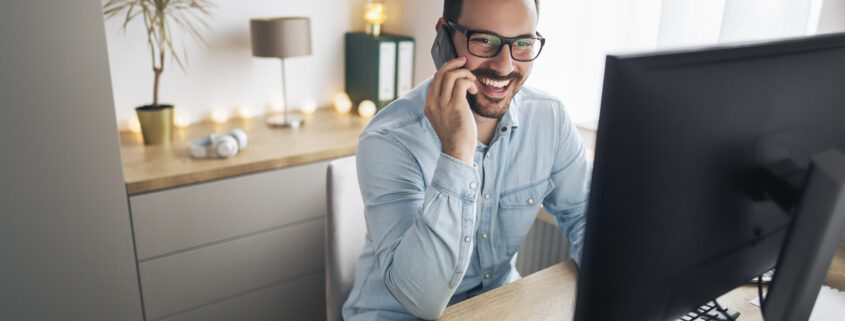 dipendente che sorride, usando il telefono per il lavoro a distanza