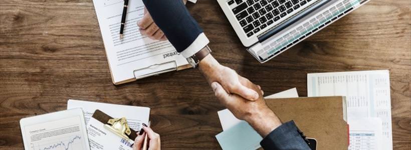 two businessmen shaking hands and using reporting