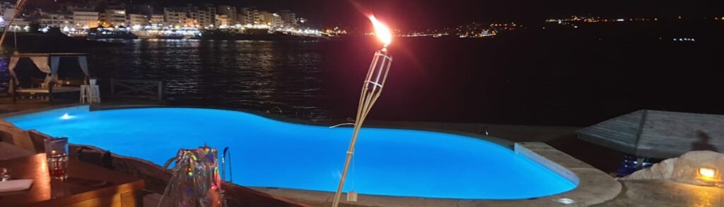 photo of pool at night, lit torch