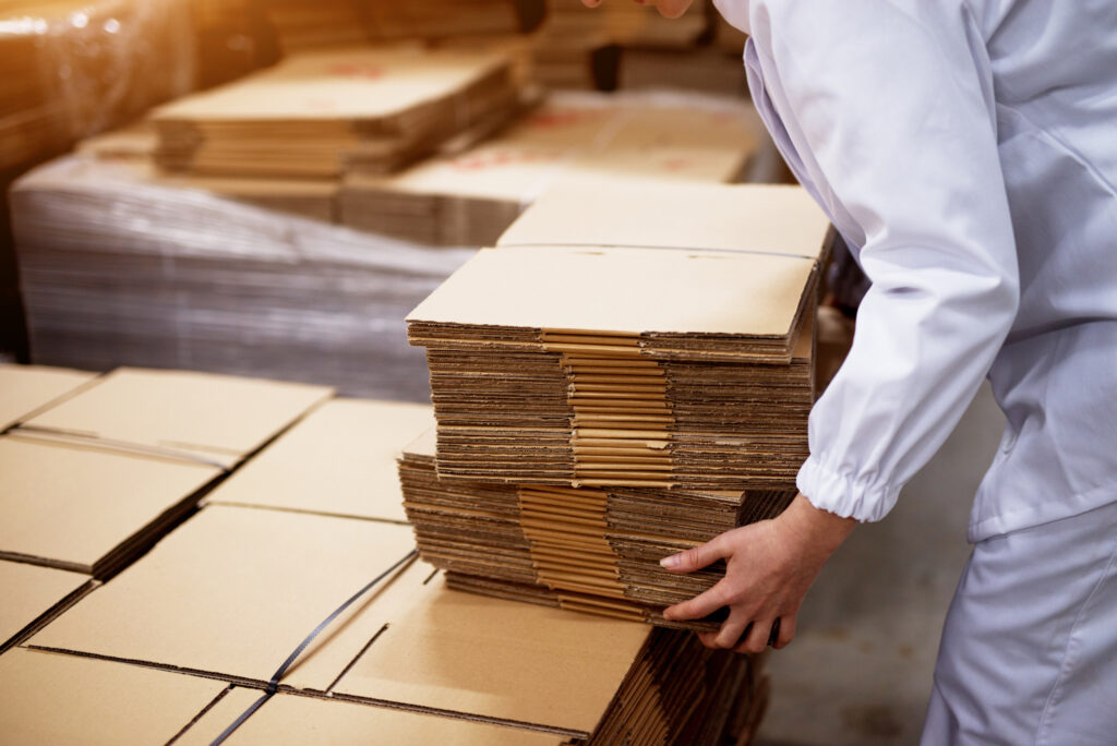 manufacturing employee stacks of folded cardboard boxes