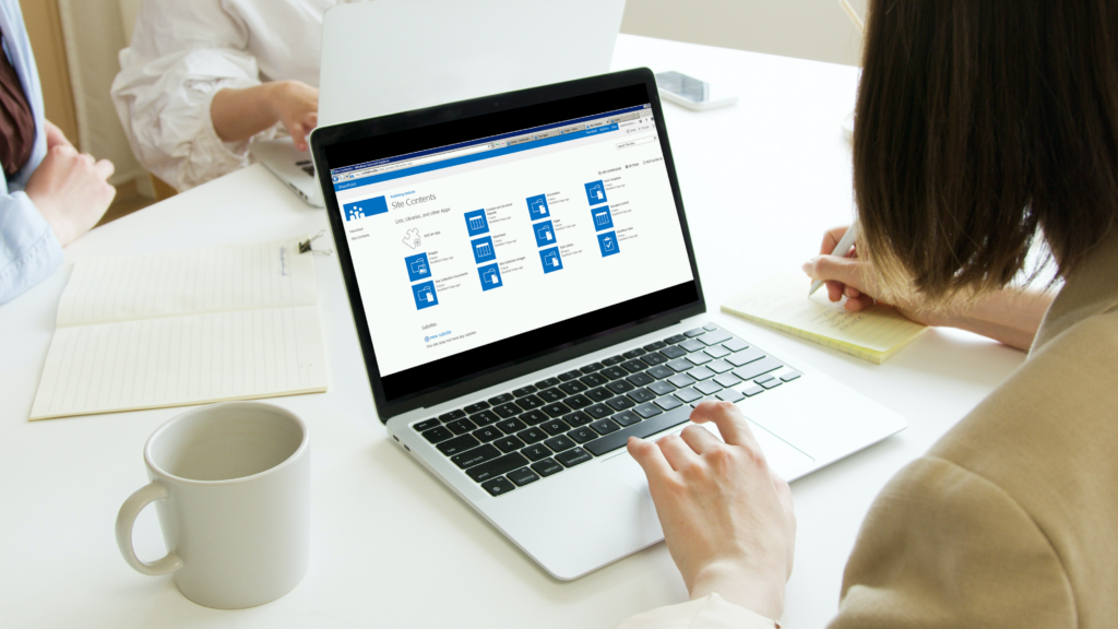 Woman using laptop during meeting showing Sharepoint