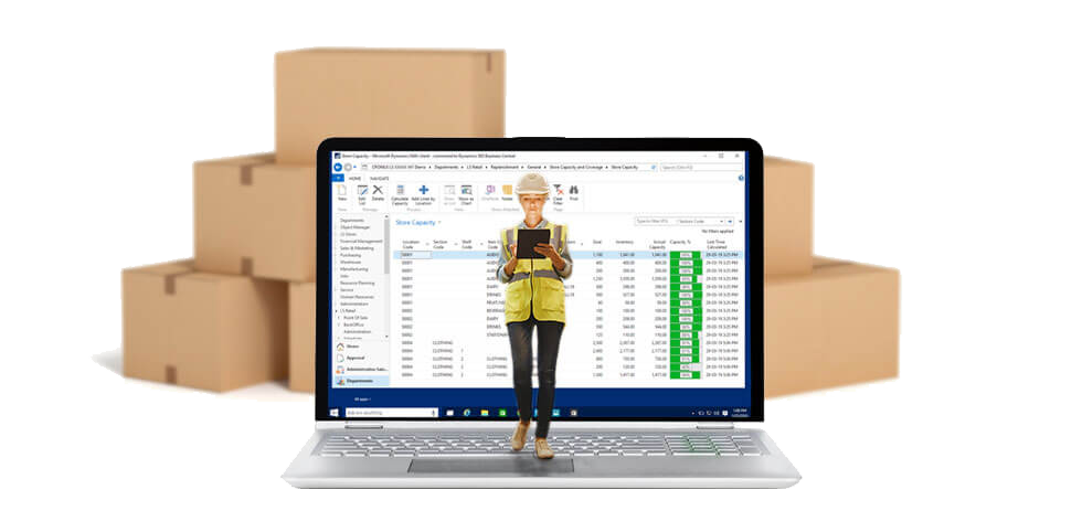 Employee wearing hardhat and vest using tablet in front of laptop displaying Microsoft Dynamics NAV in warehouse management